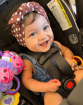 Baby girl is wearing a handmade baby head wrap from By Bella Boutique.